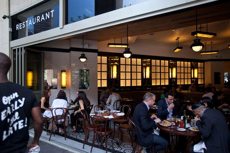 Brunch spot near Central Park with an open-air design, featuring classic bistro-style seating and a lively atmosphere. Guests enjoy a mix of casual and upscale dining, with a warm, inviting interior and a relaxed sidewalk café feel.