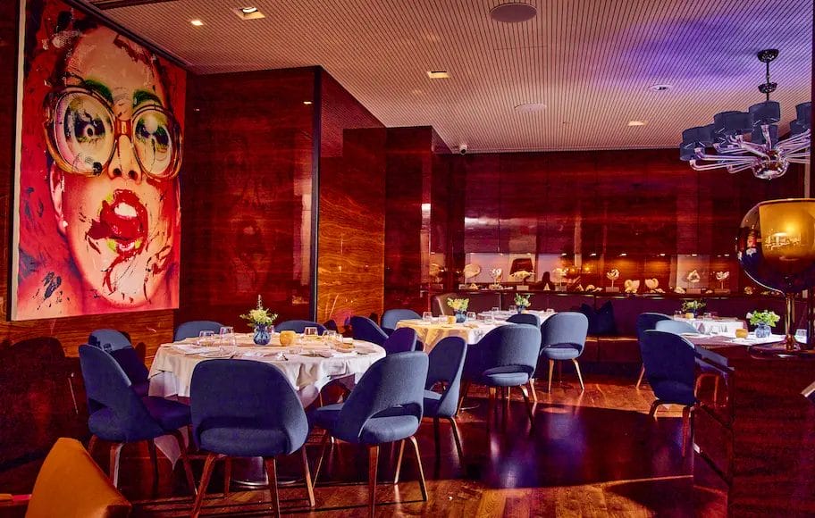 Stylish romantic restaurant near Central Park featuring modern decor, dim lighting, artistic wall designs, and intimate table settings for an upscale dining experience.