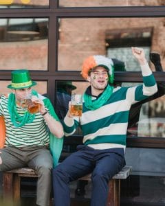 Two people enjoying some drinks in St. Patrick's Day attire