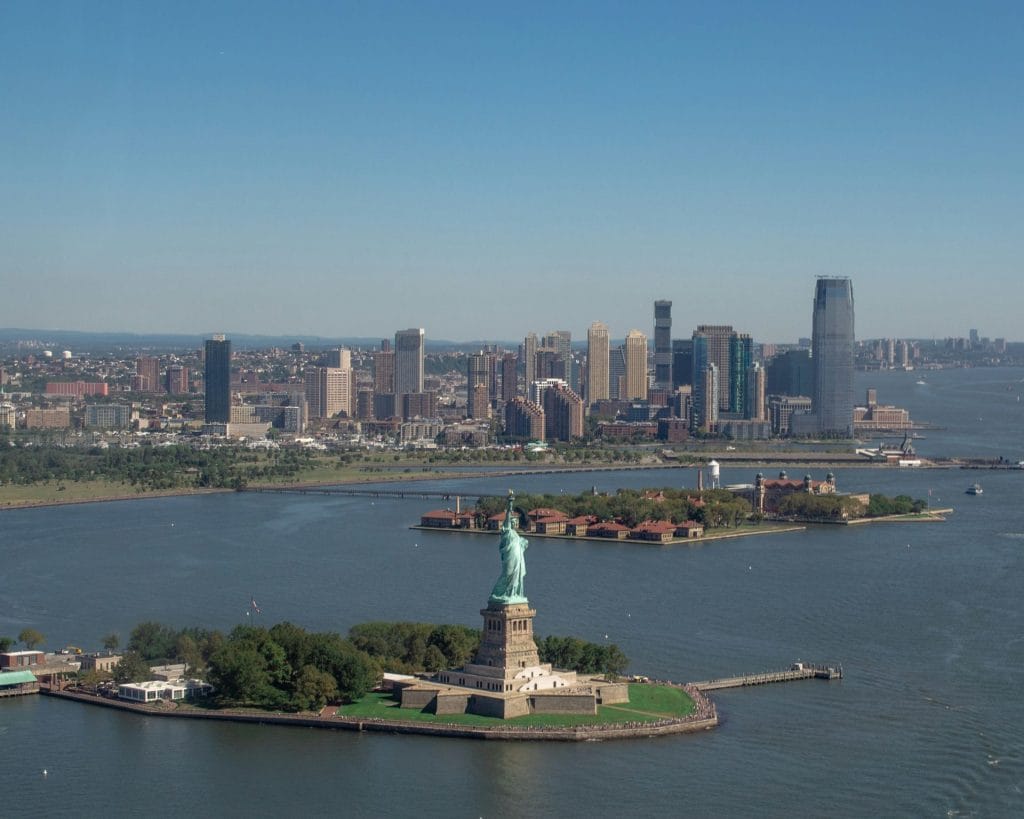 Bird's-eye view of the Statue of Liberty rising from the water, capturing its majestic presence and the beauty of the harbor