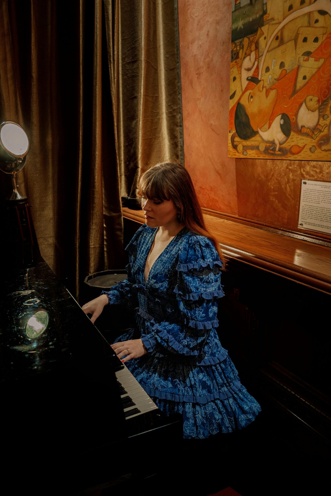 A woman in a luxury vintage blue dress playing piano