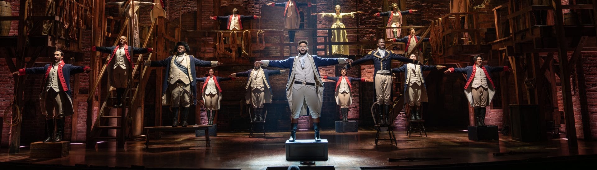 Actors from Hamilton performing on stage.