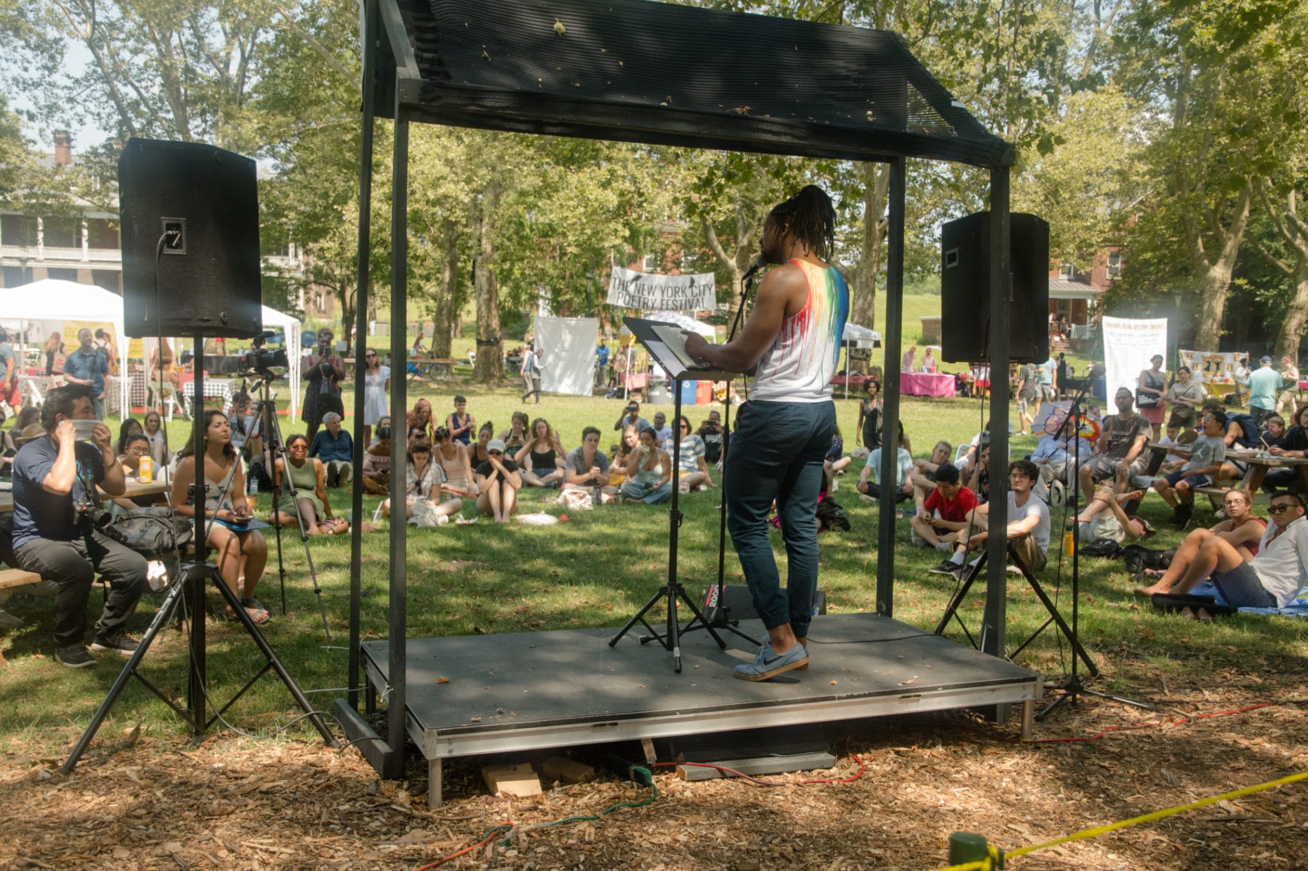 An individual reading poetry in front of a crowd at Nolan Park in Governors Island