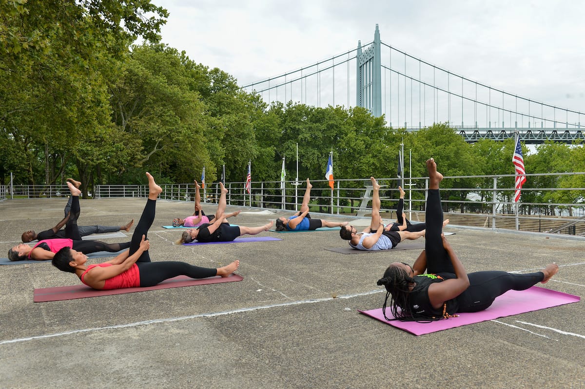 People exercising in a parking lot with the Manhattan Bridge in the back.