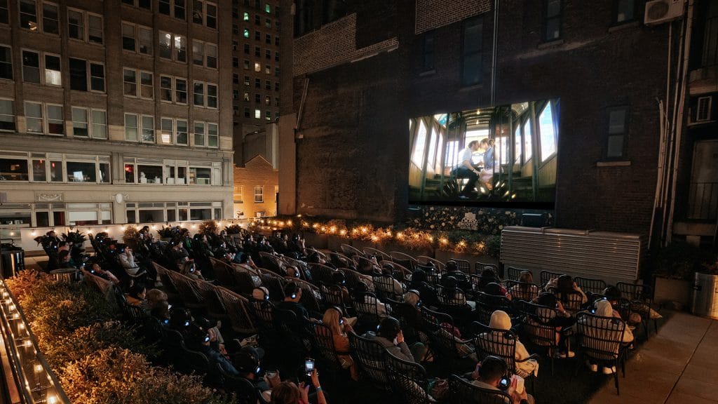 People gathered and watching an outdoor movie at Rooftop Cinema Club