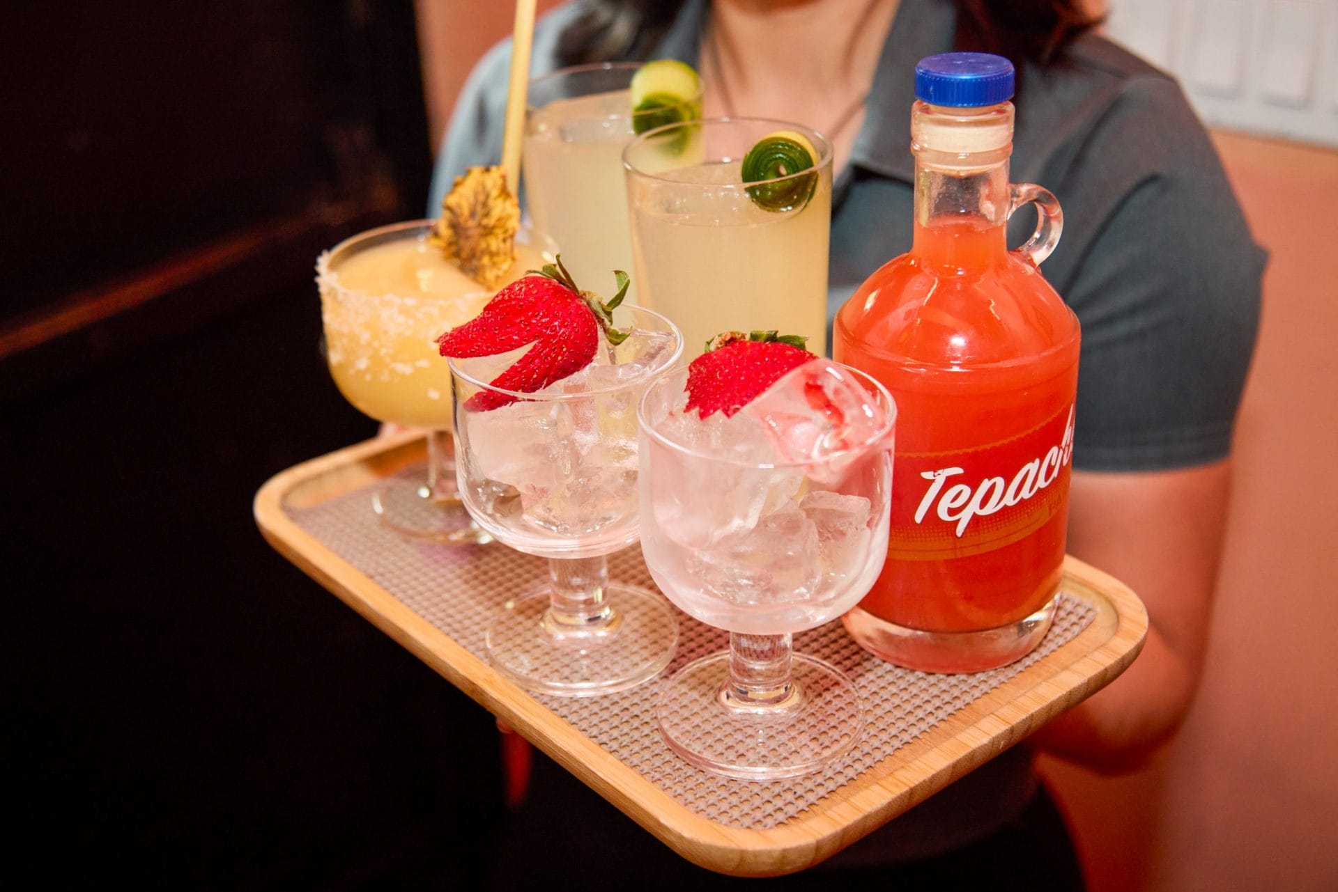 Server holding a tray with 6 different cocktails.
