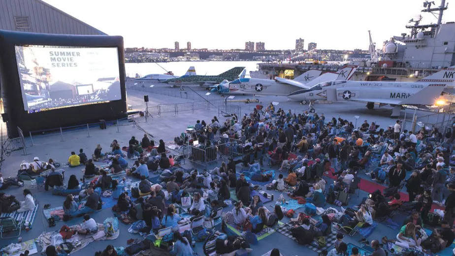 People gathered and watching an outdoor movie at the Intrepid, Sea, Air & Space Museum