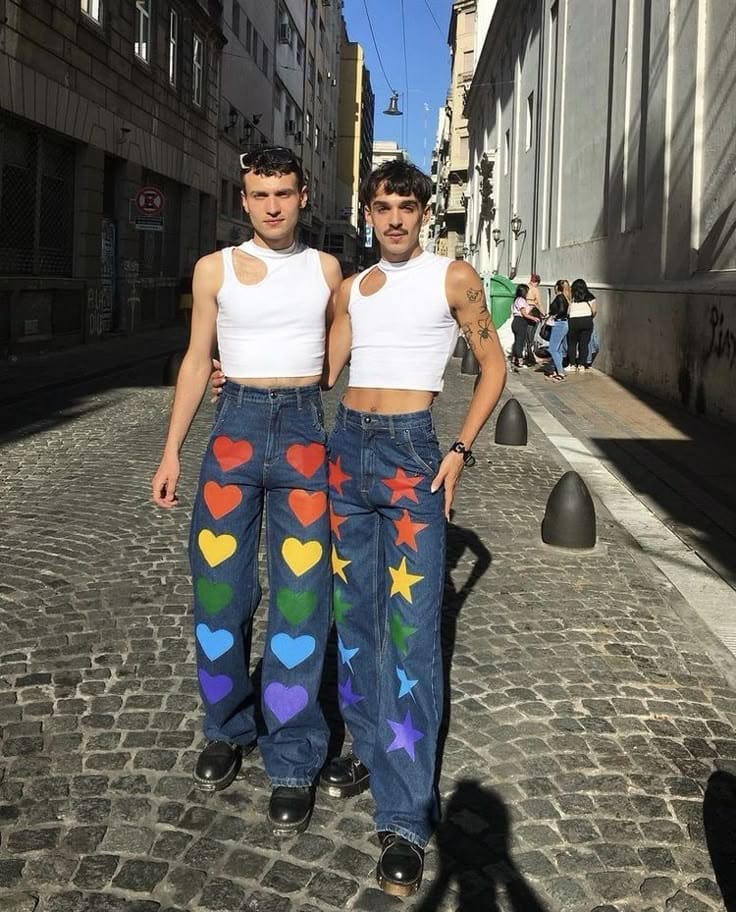 Two people wearing DIY jeans with colourful painted hearts and stars running down the leg.