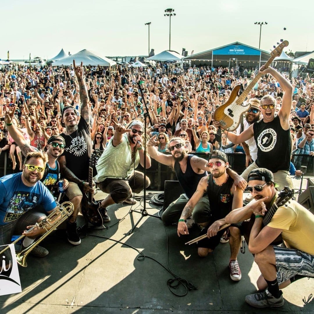 Band Oogee Wawa posing on stage with a surrounding crowd