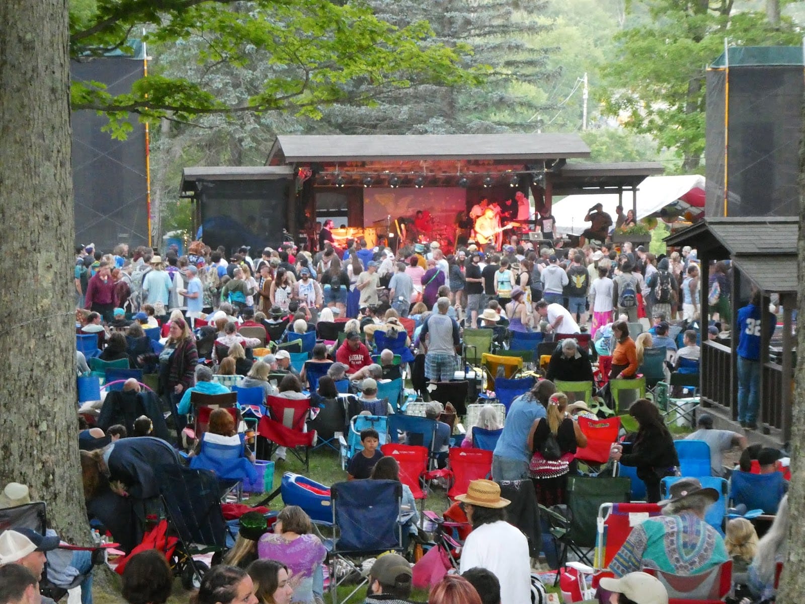 People sitting on the field in front of a stage performance.
