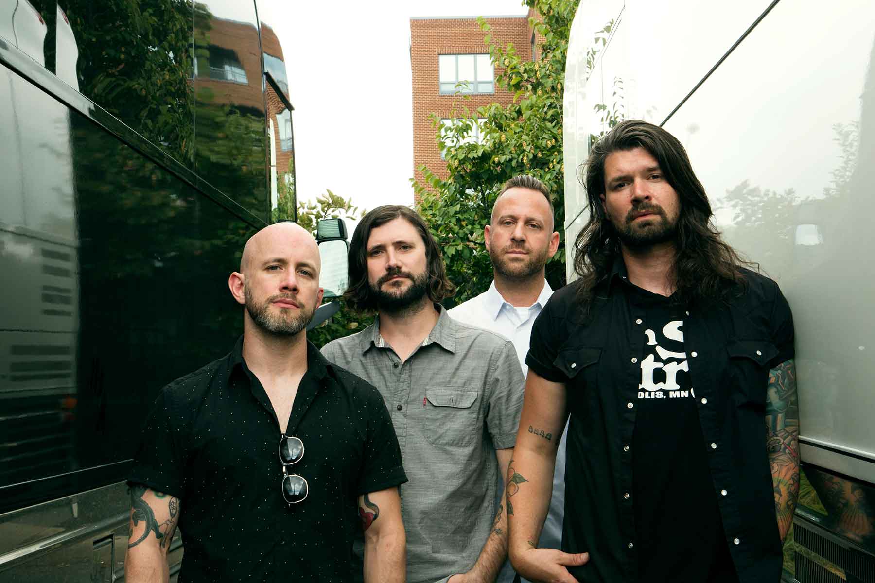 Band Taking Back Sunday posing together in between two vans